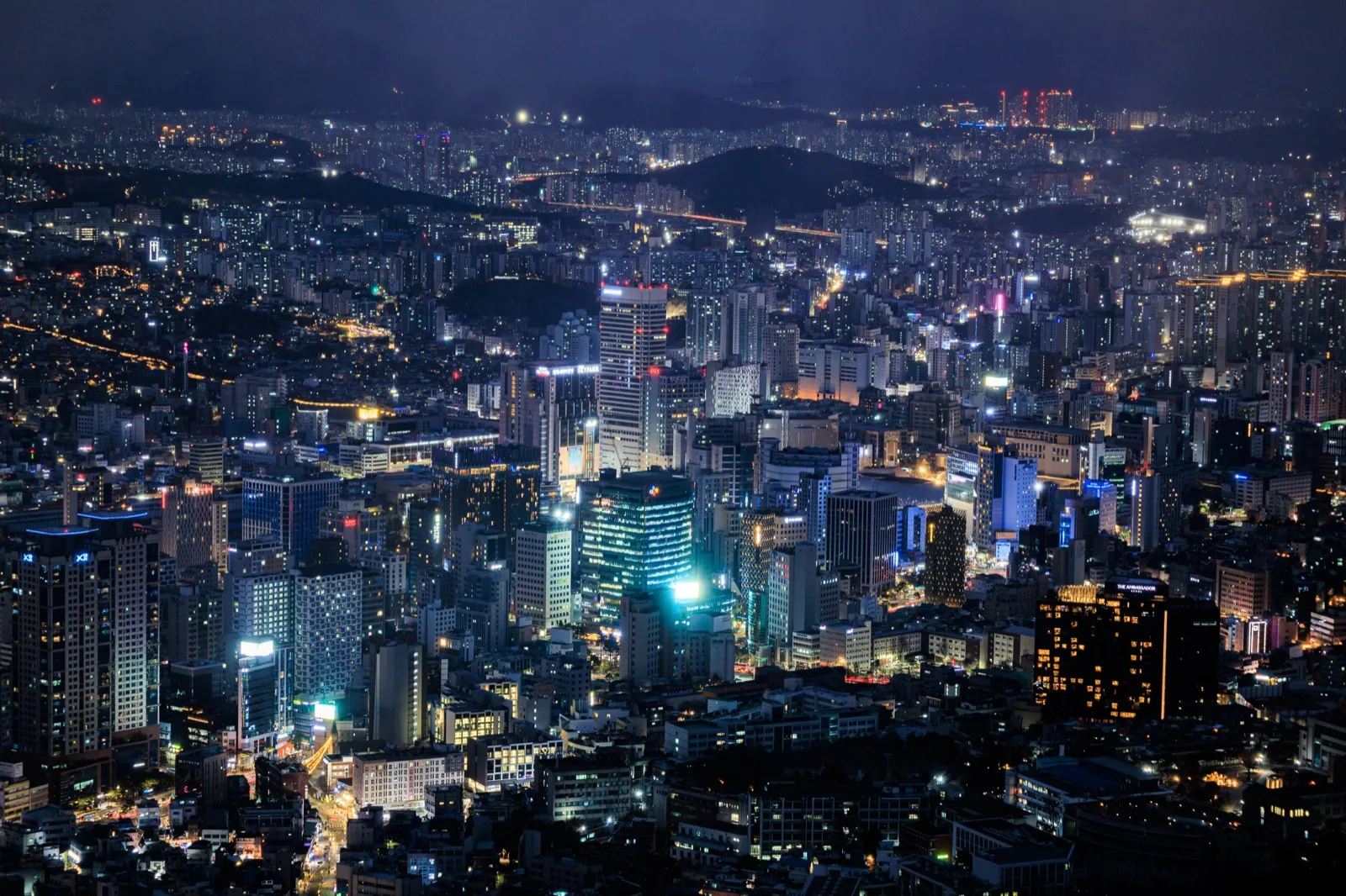 A wide night view over central Seoul with dense city lights and high-rise buildings