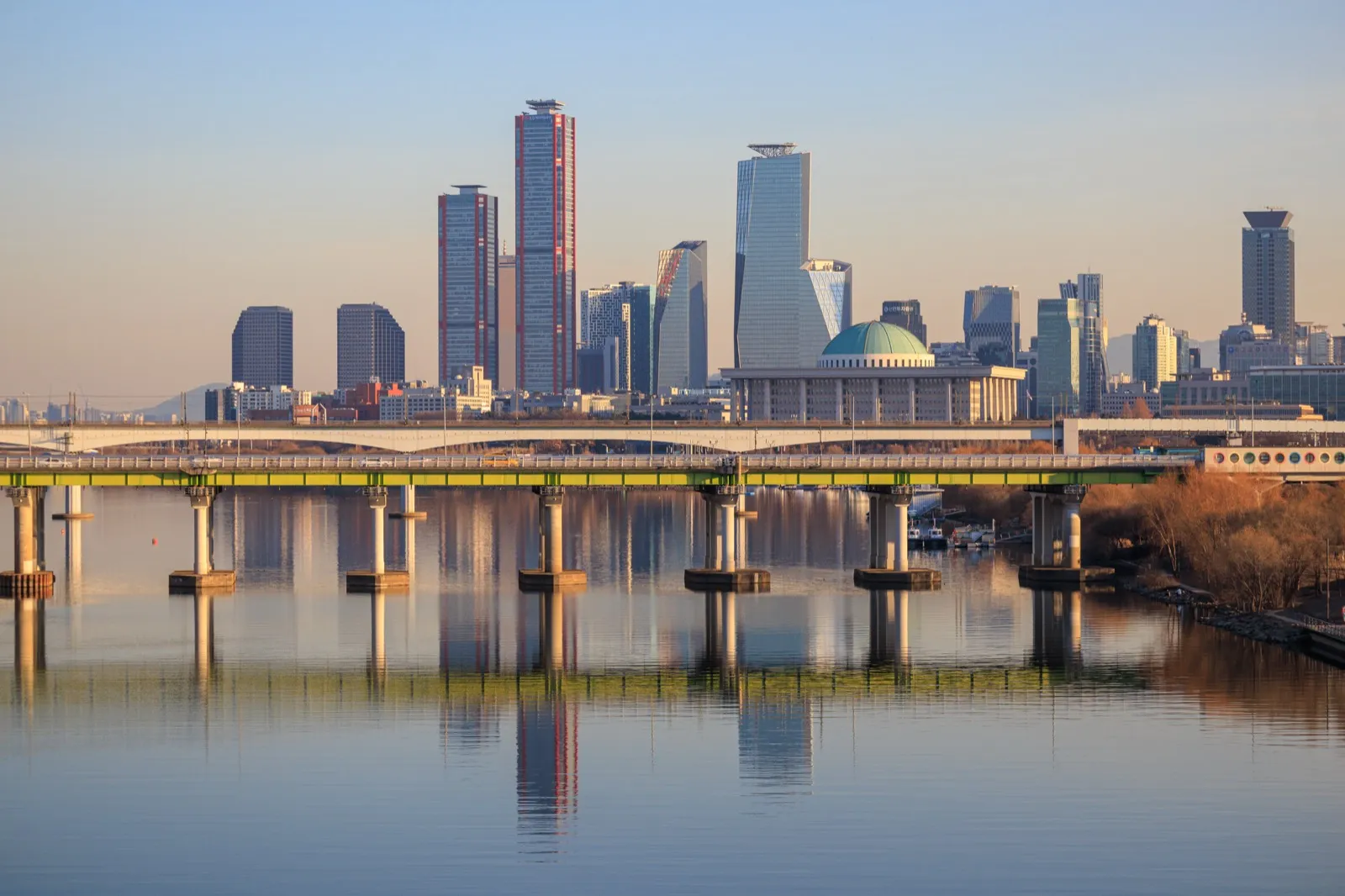 The Yeouido skyline and National Assembly building reflected in still river water at sunset
