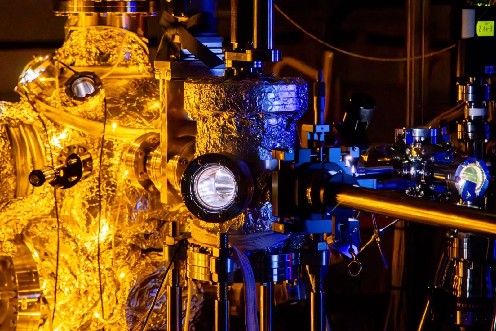 An ARPES instrument wrapped in warm holiday lights with metallic chambers and optics glowing in the dark
